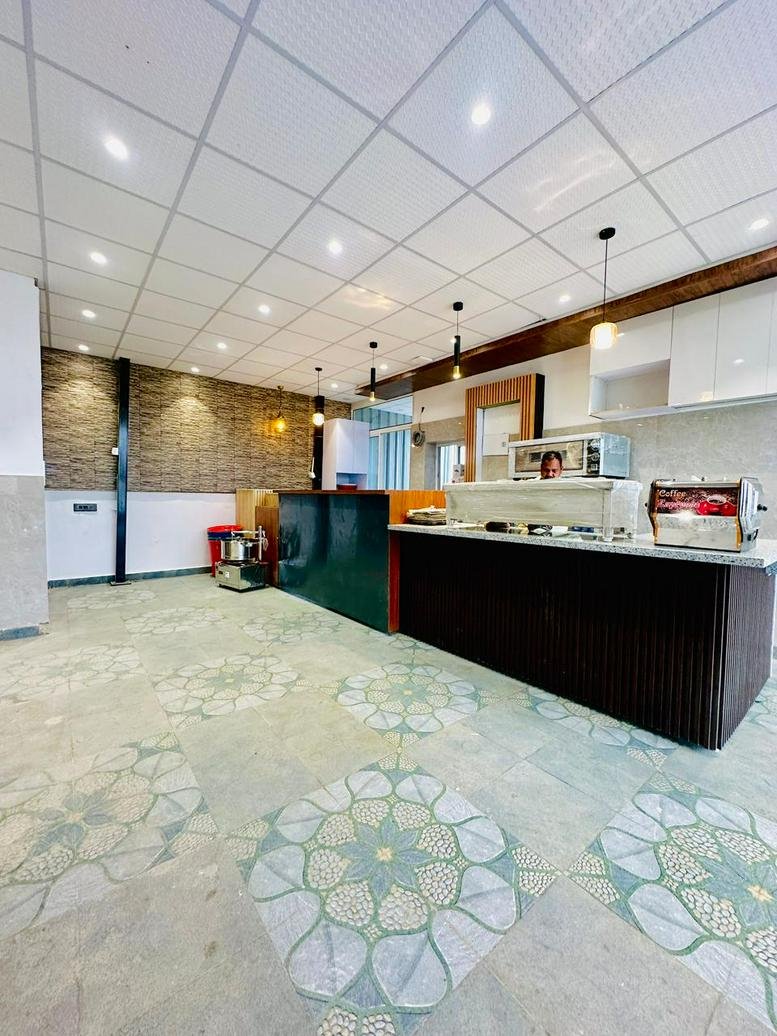 Spacious communal cafe area at Golden Glory Coworking Space with decorative tile flooring and counter.