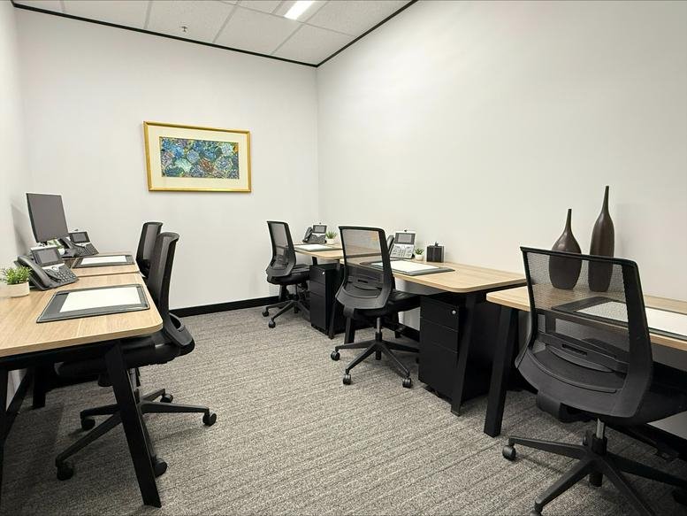 Spacious internal office with three workstations and framed artwork.