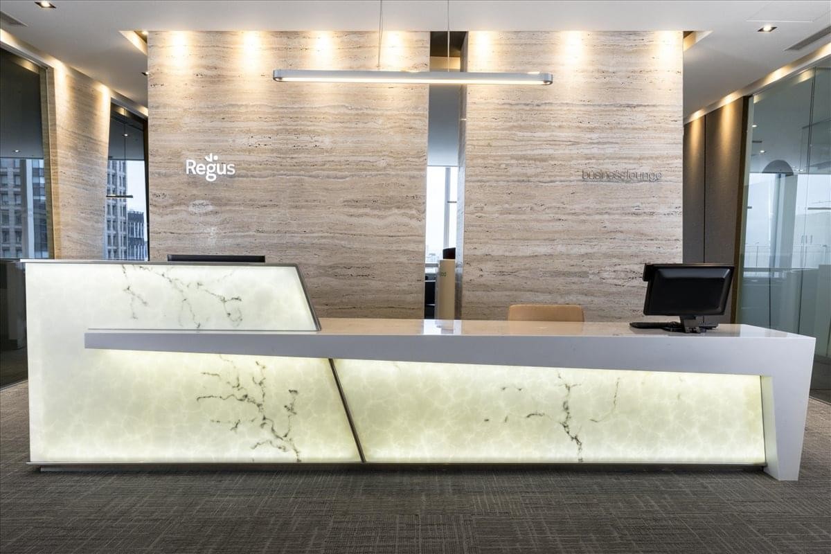Modern reception area with a minimalist white desk featuring warm backlighting and floral patterns.