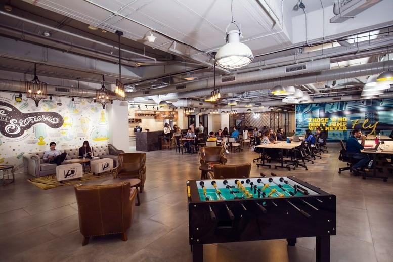 Spacious communal lounge and coworking area at 135/1, Purva Premiere with foosball and warm lighting.