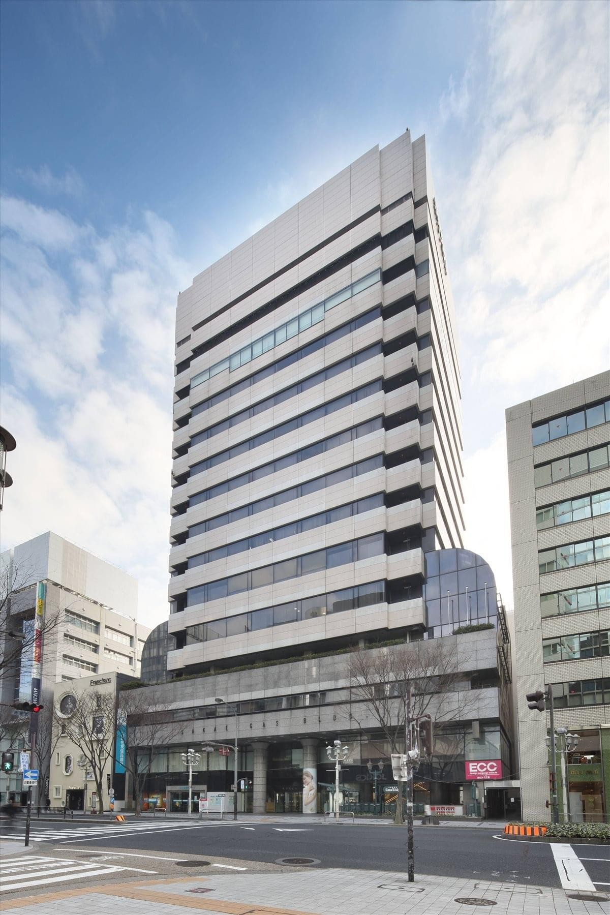 Exterior view of the multi-story Sakae Gas Building under a blue sky.