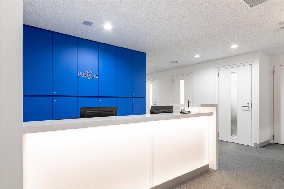 Bright reception desk with an illuminated white counter and a striking blue feature wall.