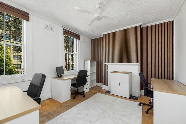 Spacious private office at 140 Commonwealth Street featuring wood-paneled walls and three workstations.