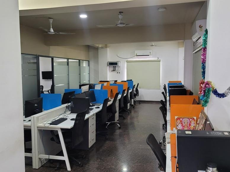 Bright open-plan workspace with multiple desk stations and ceiling fans.
