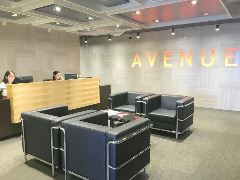 Modern reception area with a wooden front desk and black leather seating.