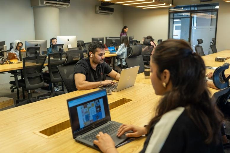 People working at shared desks in the modern workspace at Vogue Towers, 3rd Floor, 15 MM Alam Road.