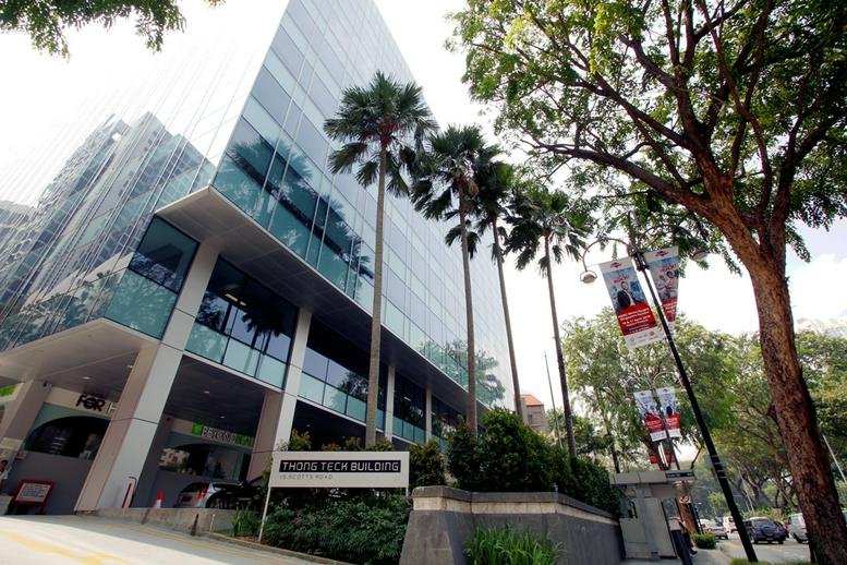 Exterior view of the glass-facade Tong Teck Building surrounded by tropical greenery.
