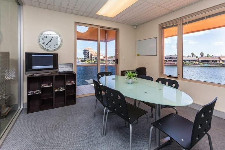 Bright meeting room with an oval glass table and large windows overlooking the water.