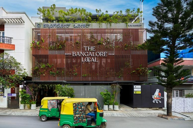 Exterior view of the multi-story building facade for The Bangalore Local with lush greenery.