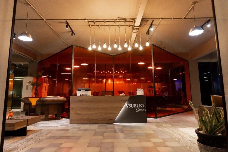Reception lobby at 16 Aurengzeb Block, New Garden Town with a wooden desk and warm pendant lighting.