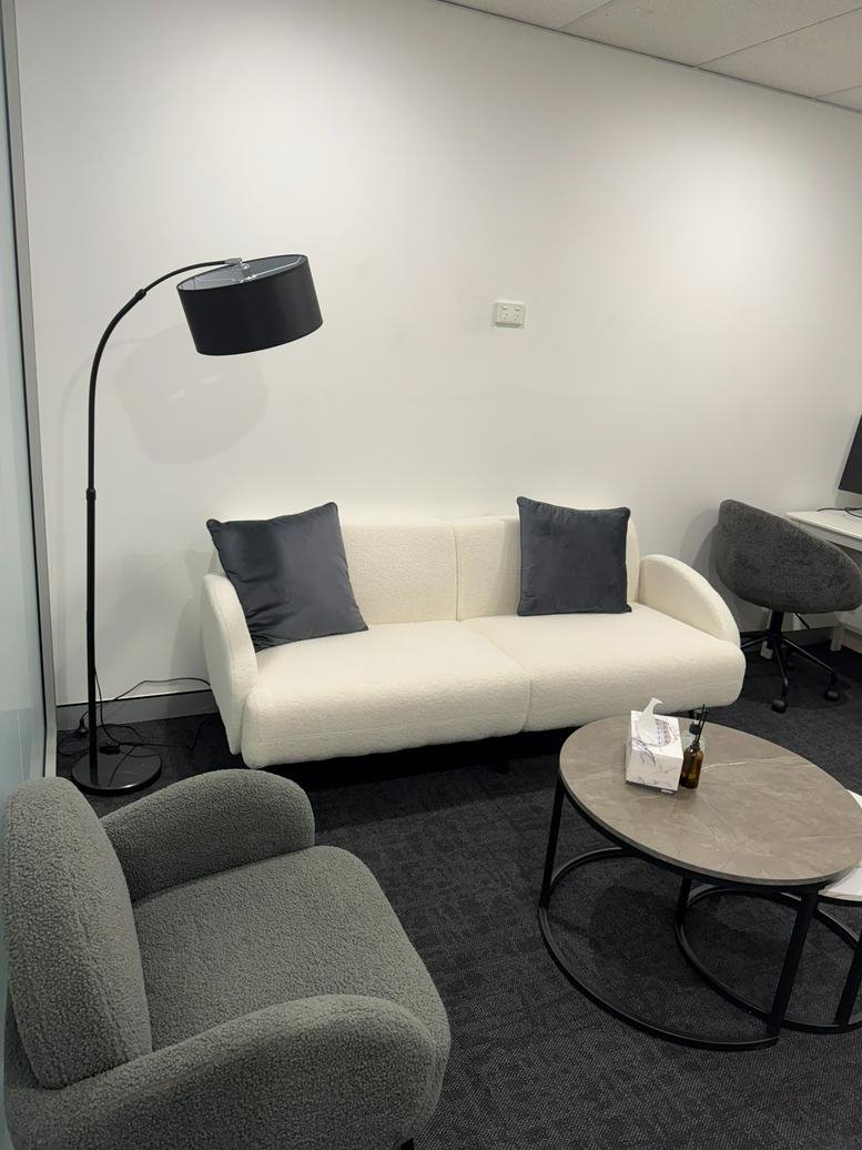 Lounge area at 166 Keira Street, Wollongong CBD with a white sofa, grey armchair, and arc floor lamp.