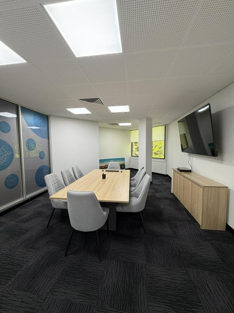 Bright meeting room at 168 Melbourne Street featuring a light wood table and modern grey chairs.