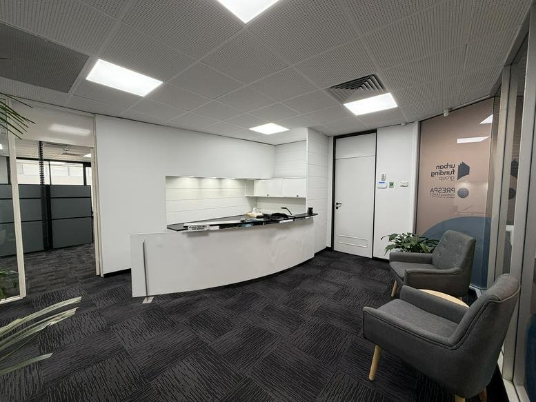 Bright reception area at 168 Melbourne Street, North Adelaide with a curved white desk and grey armchairs.