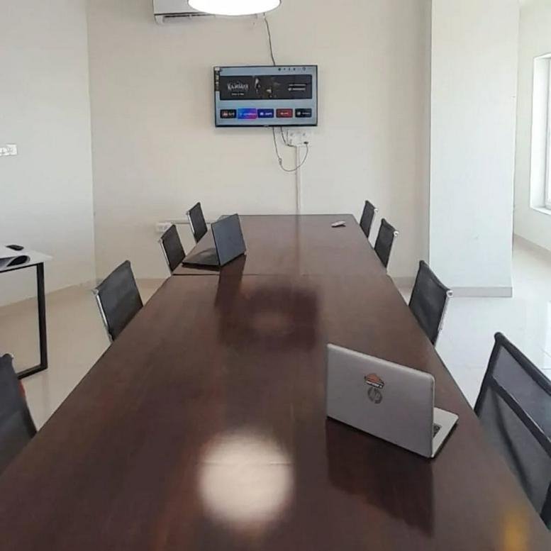 Meeting room with a long wood table, wall-mounted screen, and leather chairs at 17 Service Road.