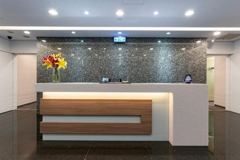 Modern reception desk with white and wood panels under a granite feature wall.