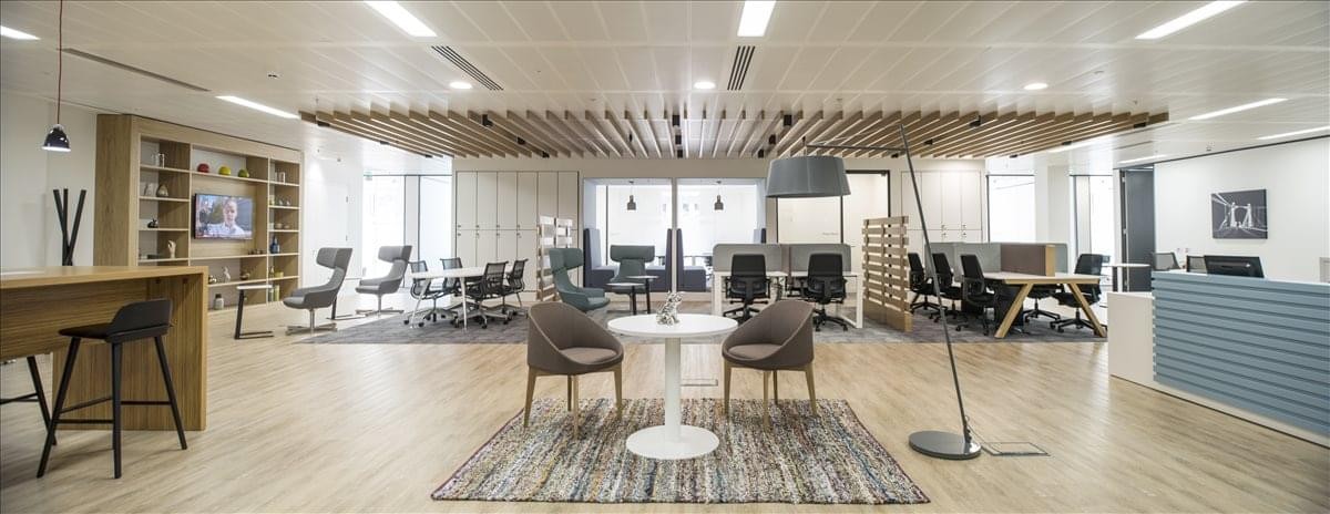 Vibrant breakout lounge with modern grey armchairs, area rugs, and built-in shelving.