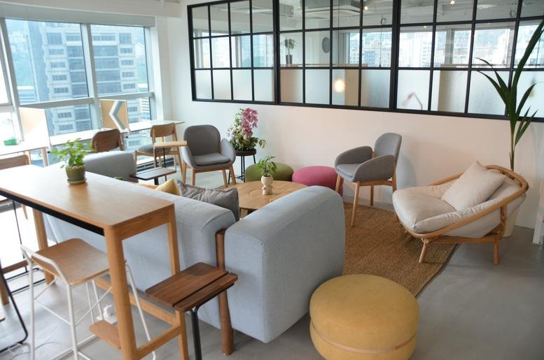 Spacious communal lounge at Honest Building with diverse seating, a large sofa, and city views through wide windows.