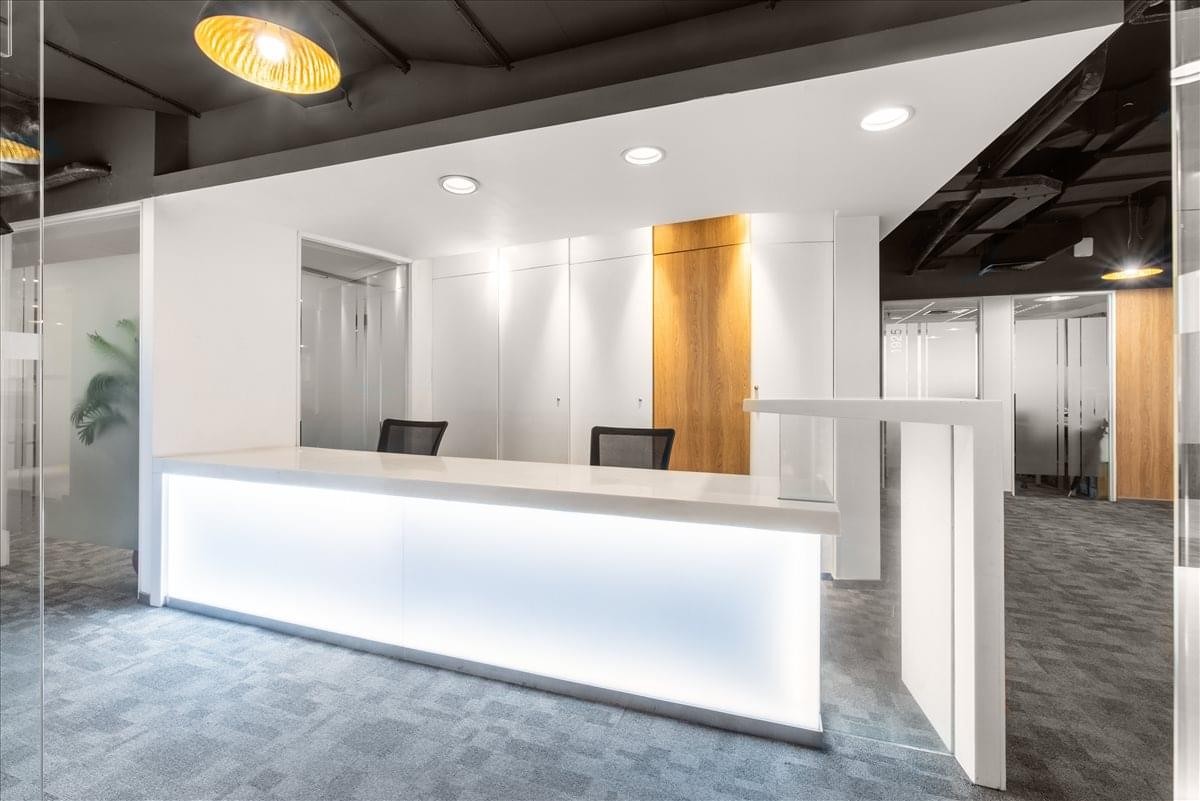 Contemporary reception area with a minimalist white backlit front desk and warm wood accents.