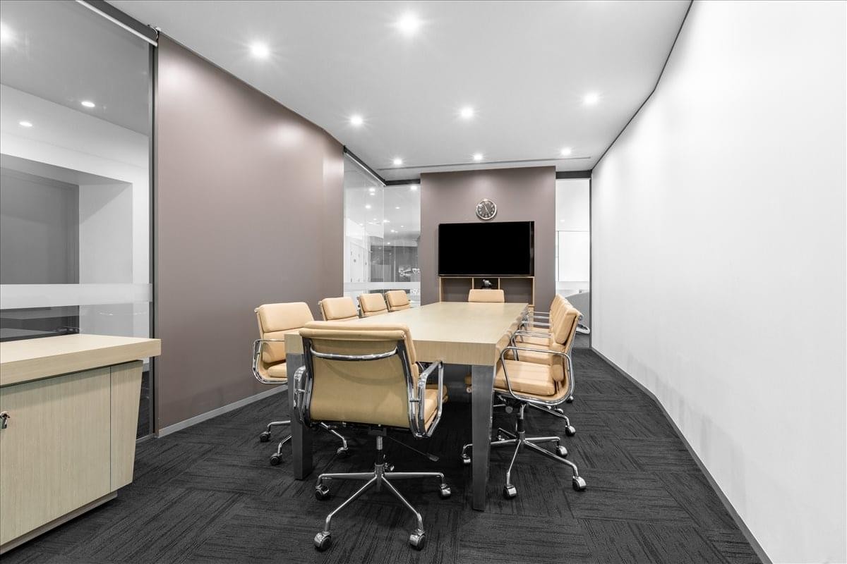 Professional boardroom at Charles Darwin Centre featuring tan leather chairs and a large wall-mounted screen.
