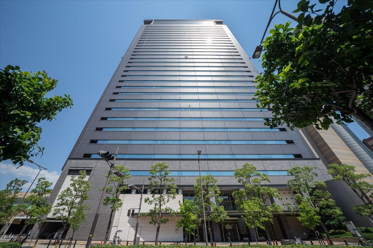 Exterior view of the tall, glass-facade 19F Namba Parks Tower under a blue sky.
