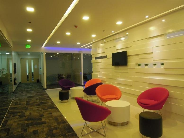 Spacious modern lounge with colorful bucket chairs and a flat-screen TV at Uptown Bonifacio.
