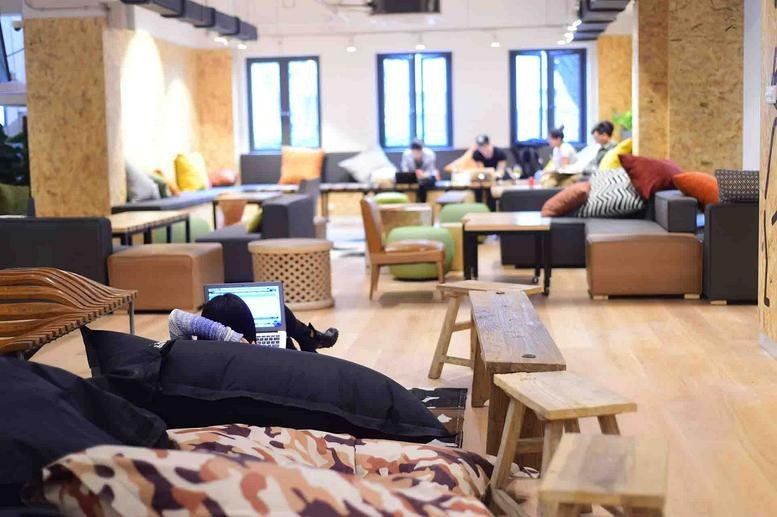 Spacious communal lounge with colorful bean bags, wooden stools, and natural light at 1F, 328 Hunan Road, Shanghai.