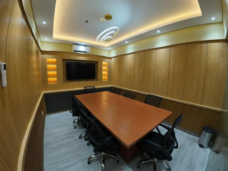 Long boardroom table in a bright room with a slatted wood ceiling and glass walls.