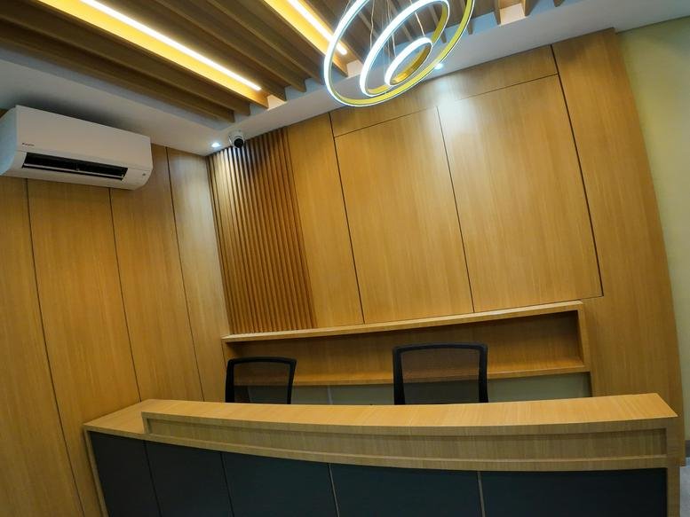 Modern wooden reception desk at The H Tower featuring a spiral pendant light.