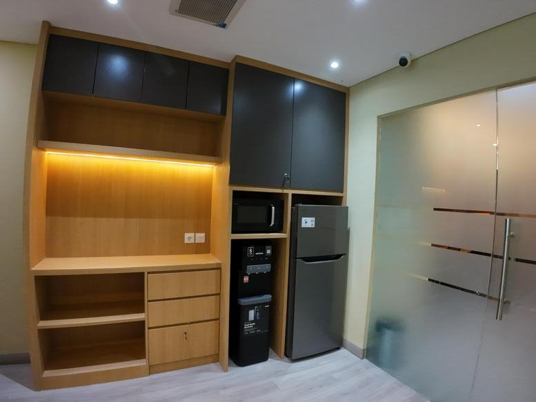 Modern kitchenette and break area at The H Tower featuring a fridge and wooden cabinetry.