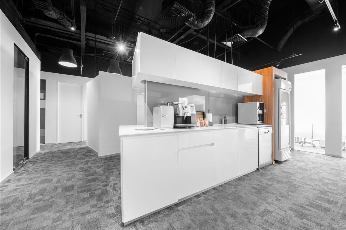 Bright white communal kitchen and break area featuring sleek cabinetry and modern coffee facilities.