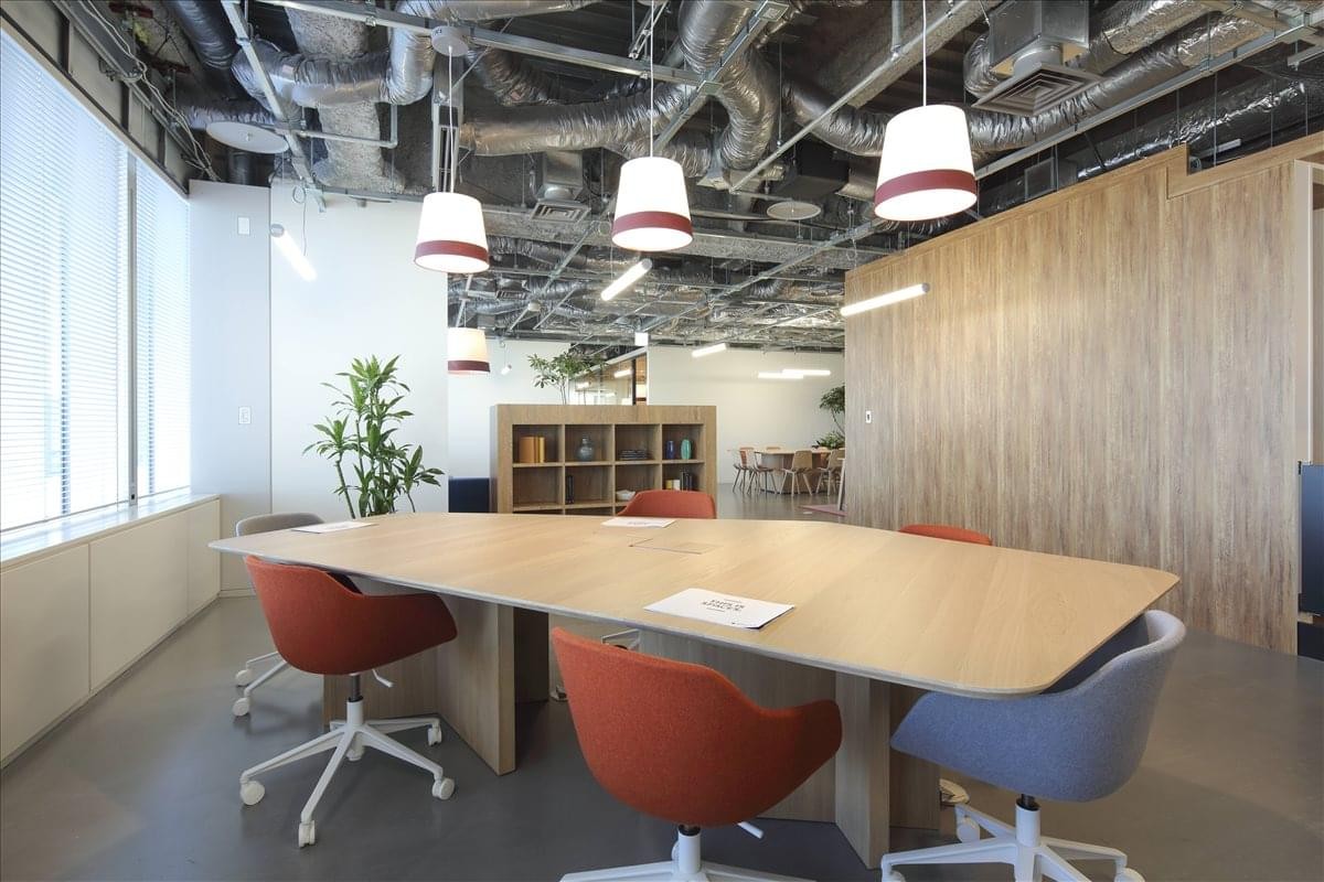 Spacious communal dining or work area with warm lighting and exposed ceiling pipes.
