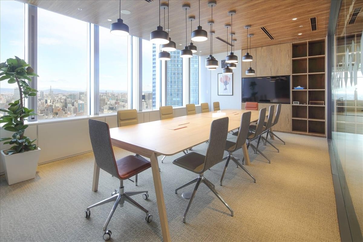 Spacious boardroom with a large light-wood table and city views.