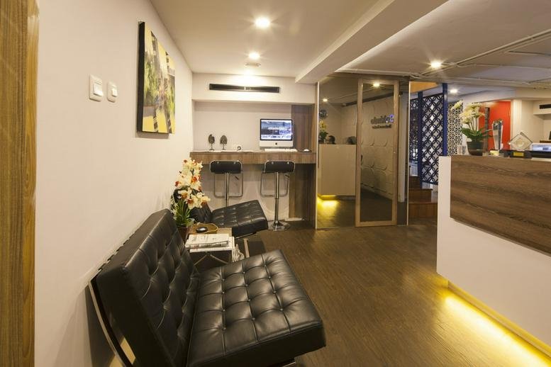 Reception area with a black tufted leather sofa and a wooden front desk with warm under-lighting.