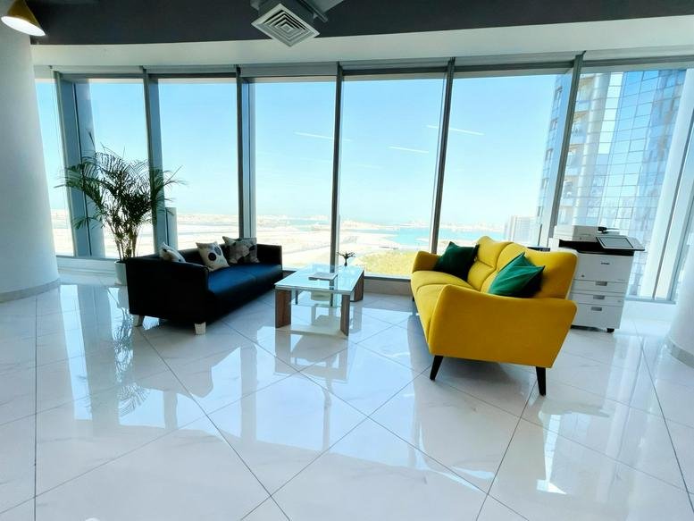 Lounge area with a dark blue sofa and a bright yellow sofa overlooking the city.
