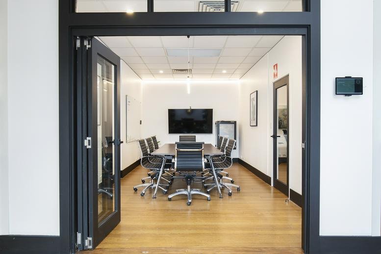 Spacious boardroom with a large screen and black leather chairs at ACTIVATE Workspaces, 239 King Street.