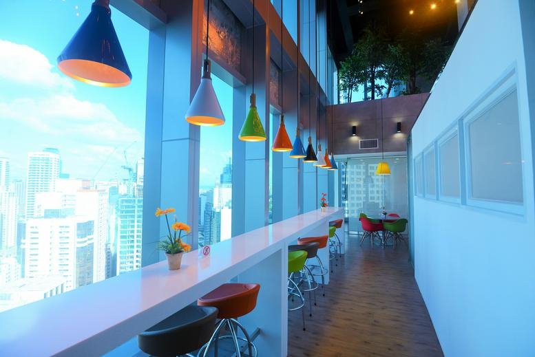 Vibrant communal breakout area at 23F Tower 6789 with colorful pendant lights and city views.