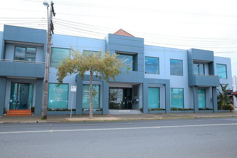 Modern two-story blue-grey office building facade with large glass windows.