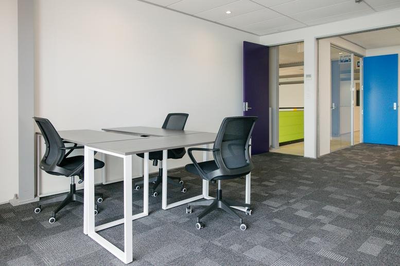 Bright private office with three workstations, ergonomic chairs, and colourful doors.