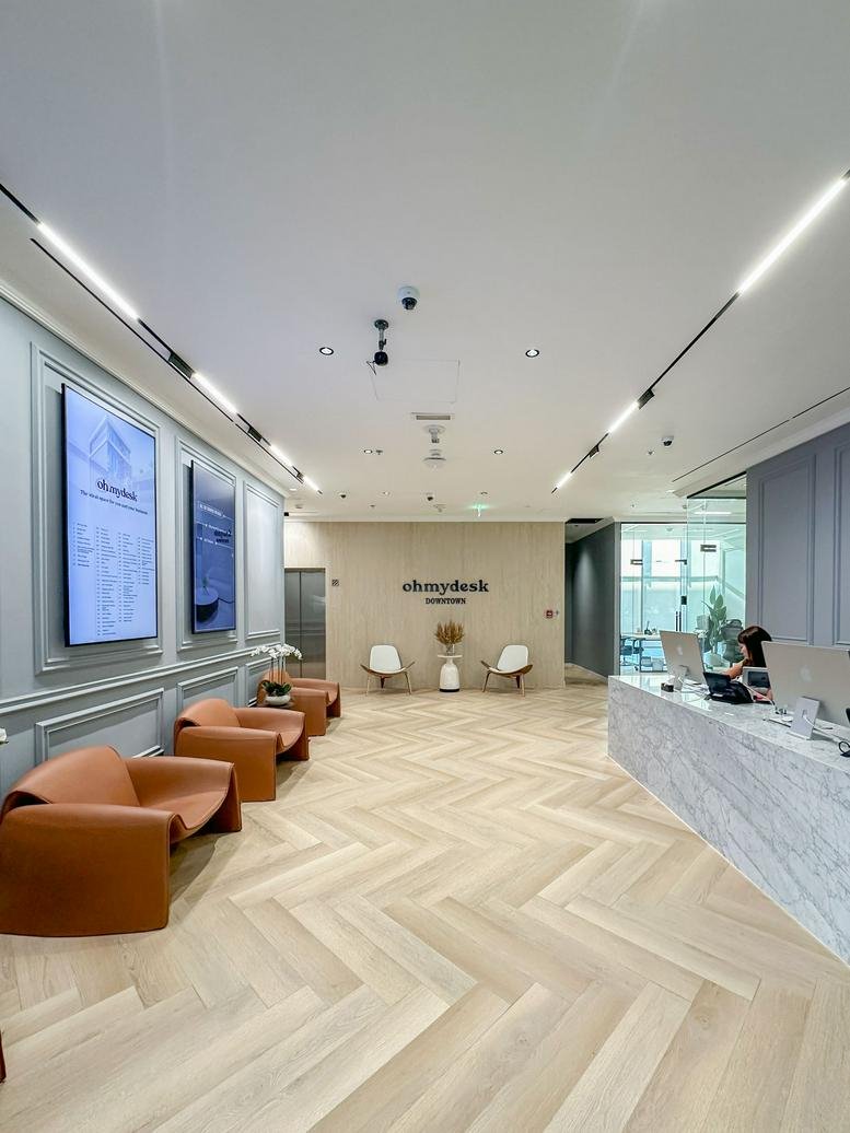 Spacious reception area at Al Fattan Currency House with marble desk and chevron wood floors.