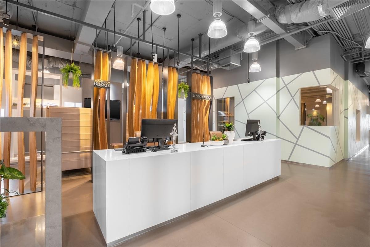 Minimalist white reception desk accented by warm wood slat partitions and modern pendant lighting.