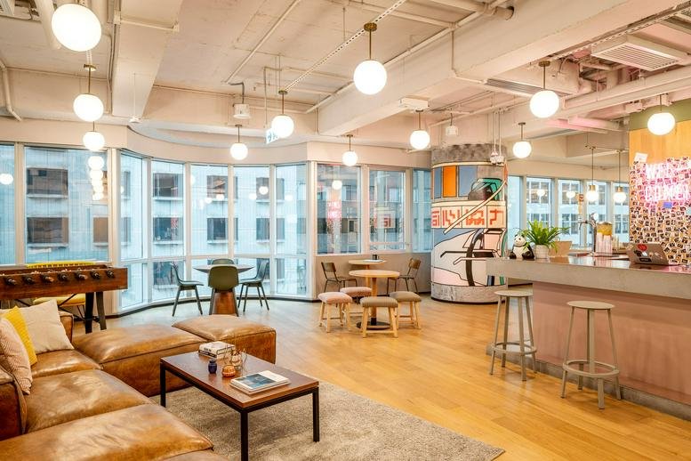 Wide-angle view of a vibrant café-style lounge with diverse seating and city views.