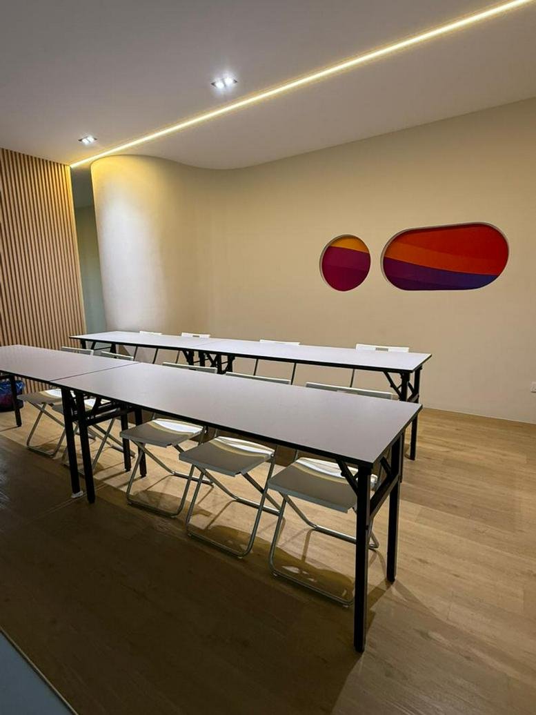 Seminar-style training room with folding white tables and colorful circular wall art.