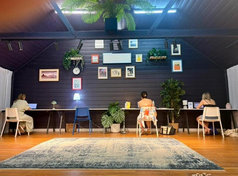 Wide-angle view of the colorful coworking area at Play Date Workspace with people at long desks.