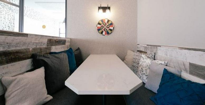 Bright breakout nook at City House with plush pillows and a white geometric table.