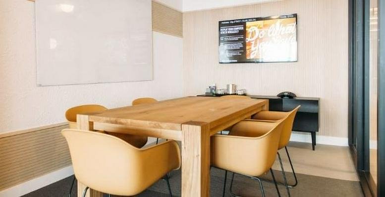 Meeting room at City House, 36 Robinson Road with a large timber table, tan chairs, and a whiteboard.