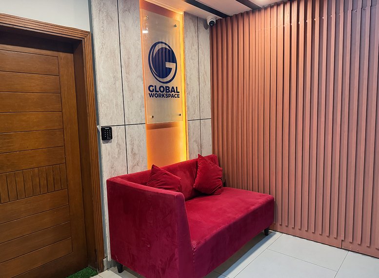 Entrance of 37-J Rafi Shamsi Road, Block 6 P. E. C. H. S, Karachi featuring a red velvet sofa and branded sign.