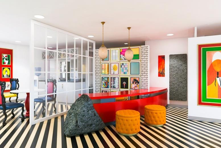 Vibrant reception area with a red desk, orange ottomans, and a gallery wall of art.
