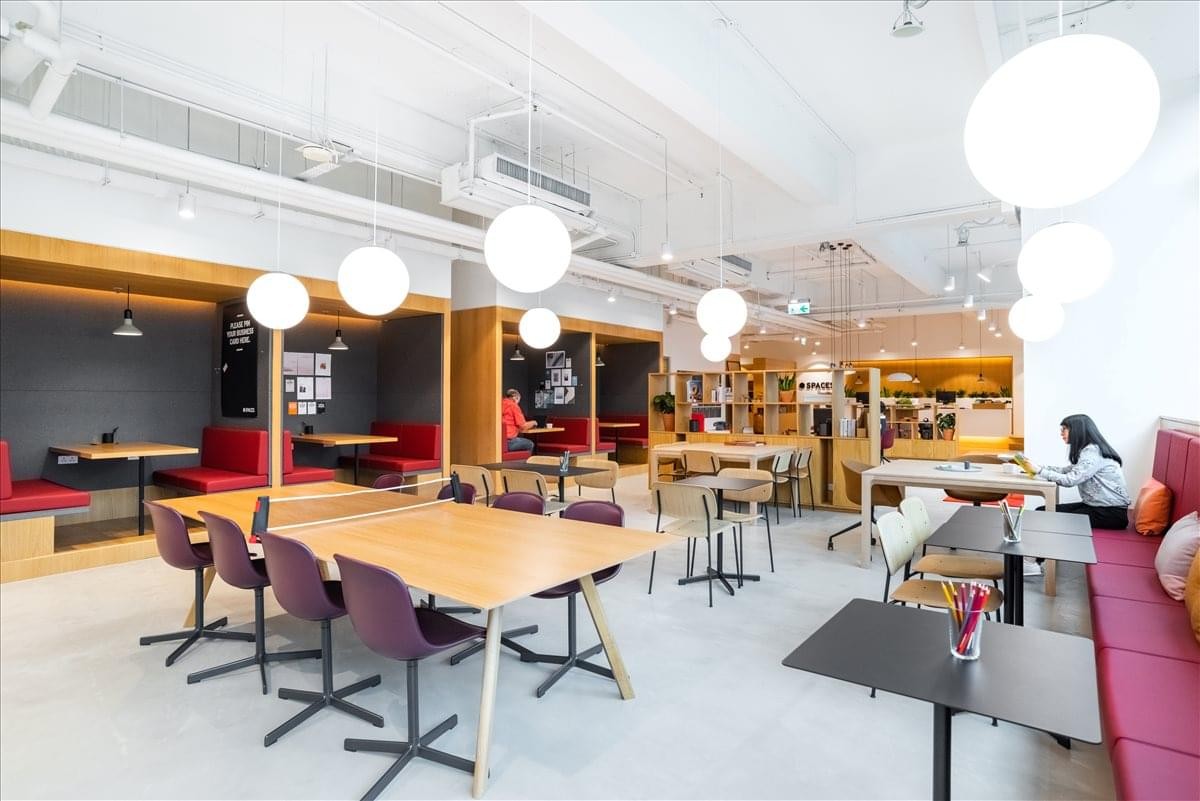 Spacious communal dining area with various seating styles and globe pendant lighting.