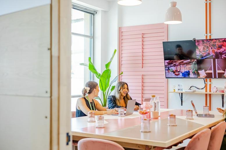 Bright meeting room at 39-47 Lasso Road with pink shutters and video conferencing screens.