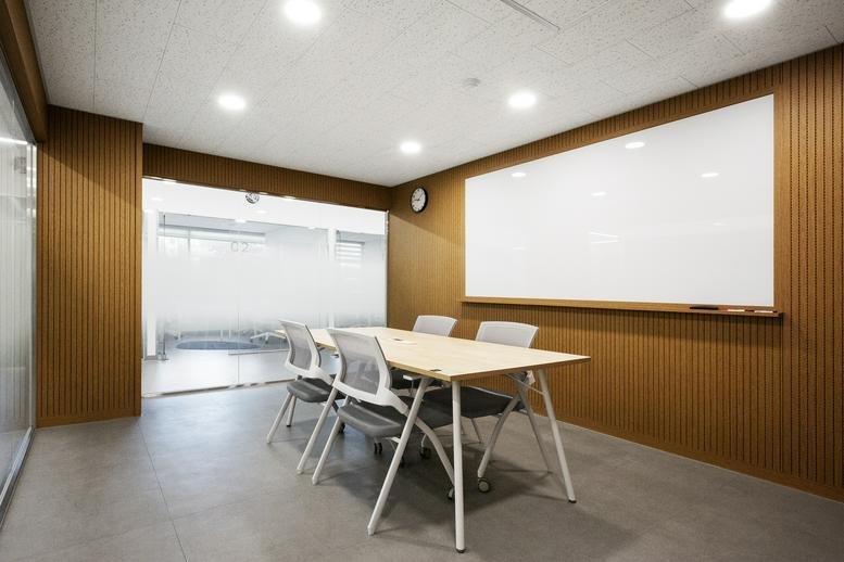 Meeting room at MoA Studio8 DDP with a large whiteboard and wooden wall paneling.